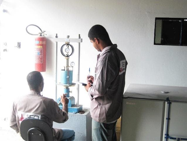 Técnicos da Geobahia operando prensa de ensaio em laboratório de solos